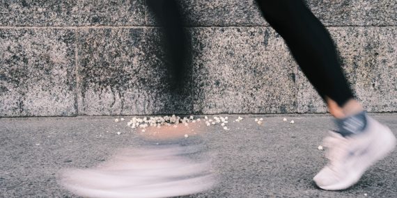 a person walking on a sidewalk near a wall